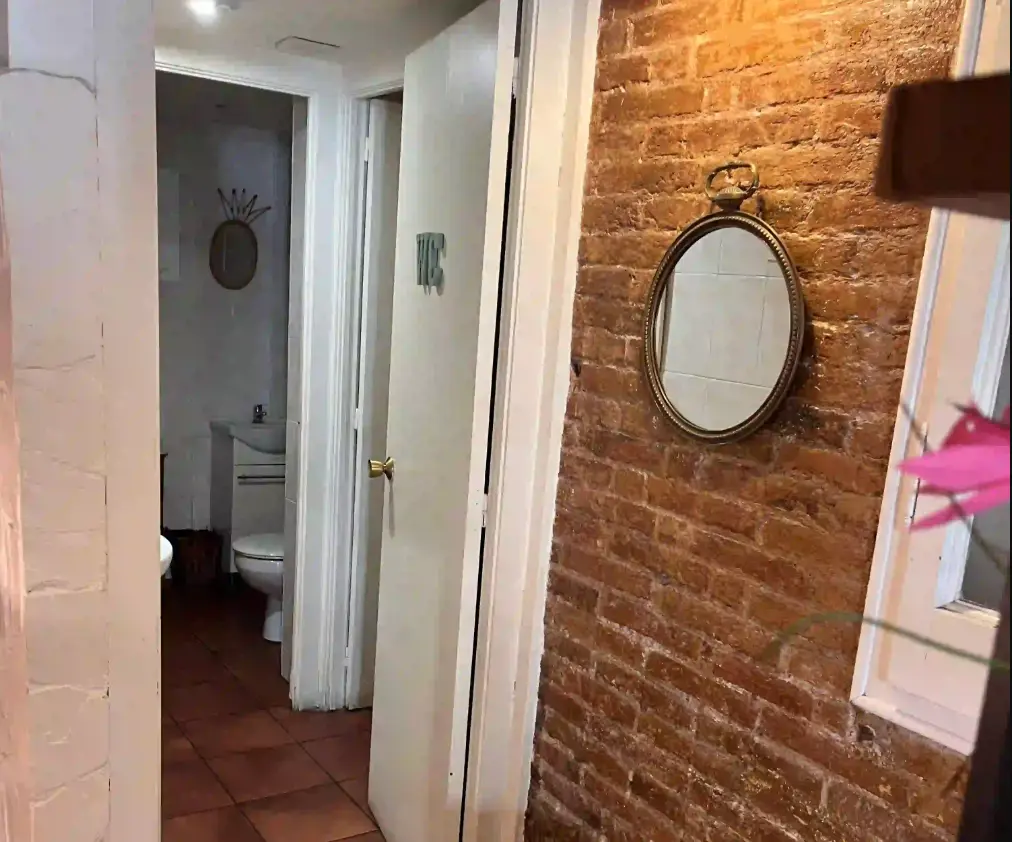 Acceso lavabos espejo bar calle Arago Zona de mesas junto a la puerta de entrada acristalada en cafetería brunch con licencia C2 en traspaso en la Diagonal, Barcelona.