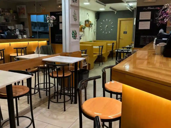 Interior con barra, mesas y espejo decorativo en bar cafetería en traspaso en Pasaje Sant Gervasi, Barcelona